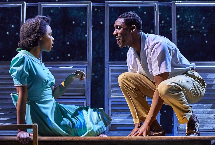 The production of Small Island featuring CJ Beckford and Leah Harvey who are sat on stage, facing each other and talking